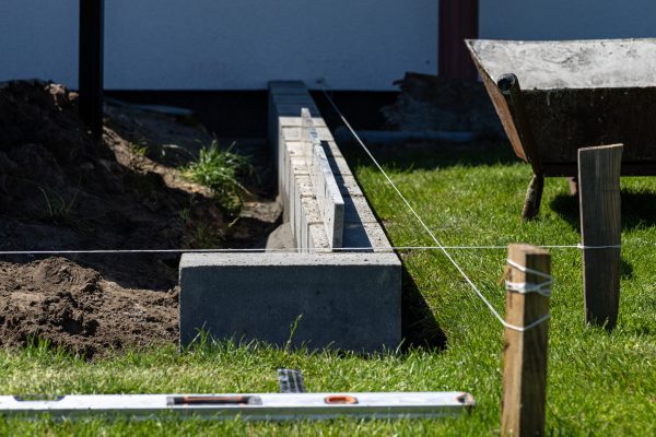 Marking out concrete block foundations for the terrace behind the house using string.